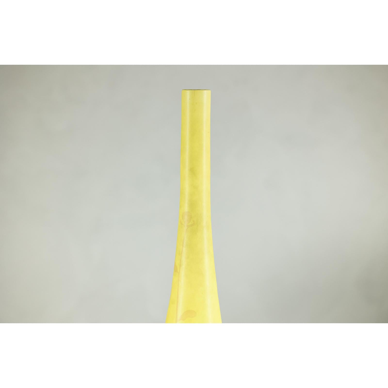 Close-up of tall skinny yellow ceramic vase with hand-painted flowers, narrow neck, on a light gray background.