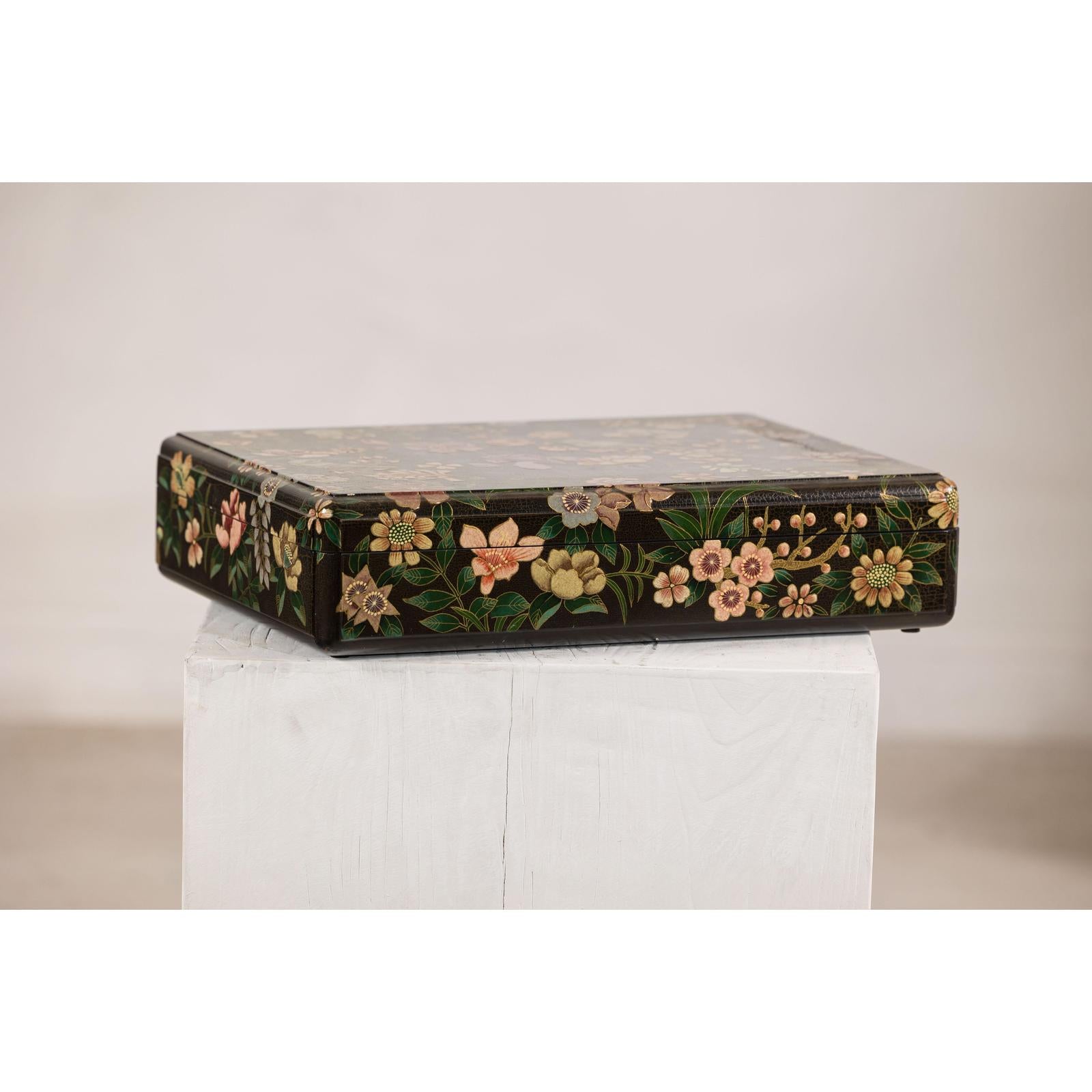 Black lacquer box with floral and bird design, felt interior, displayed on a white wooden pedestal.