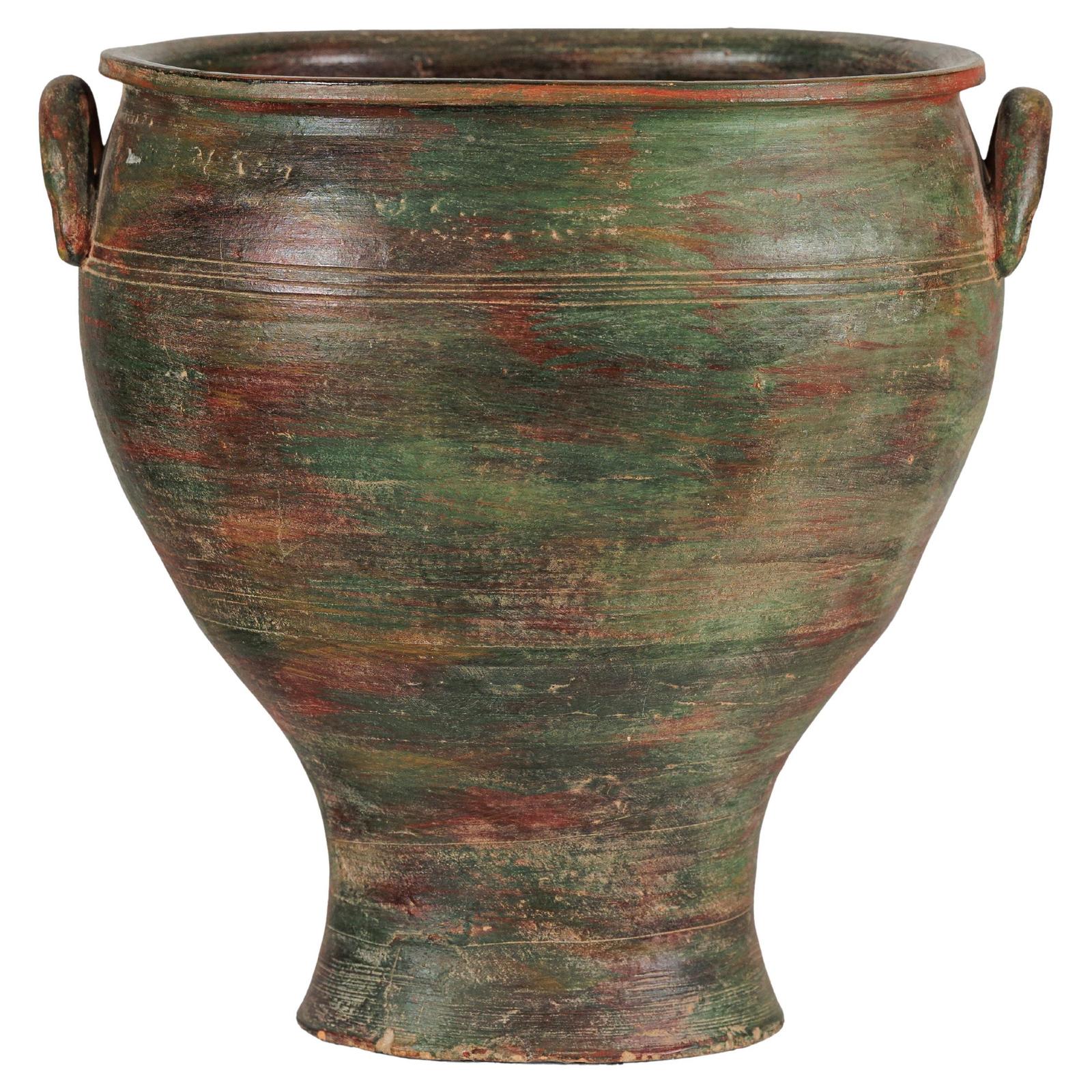 Close-up of vintage ceramic planter with weathered green, brown, and red finish and two small side handles.