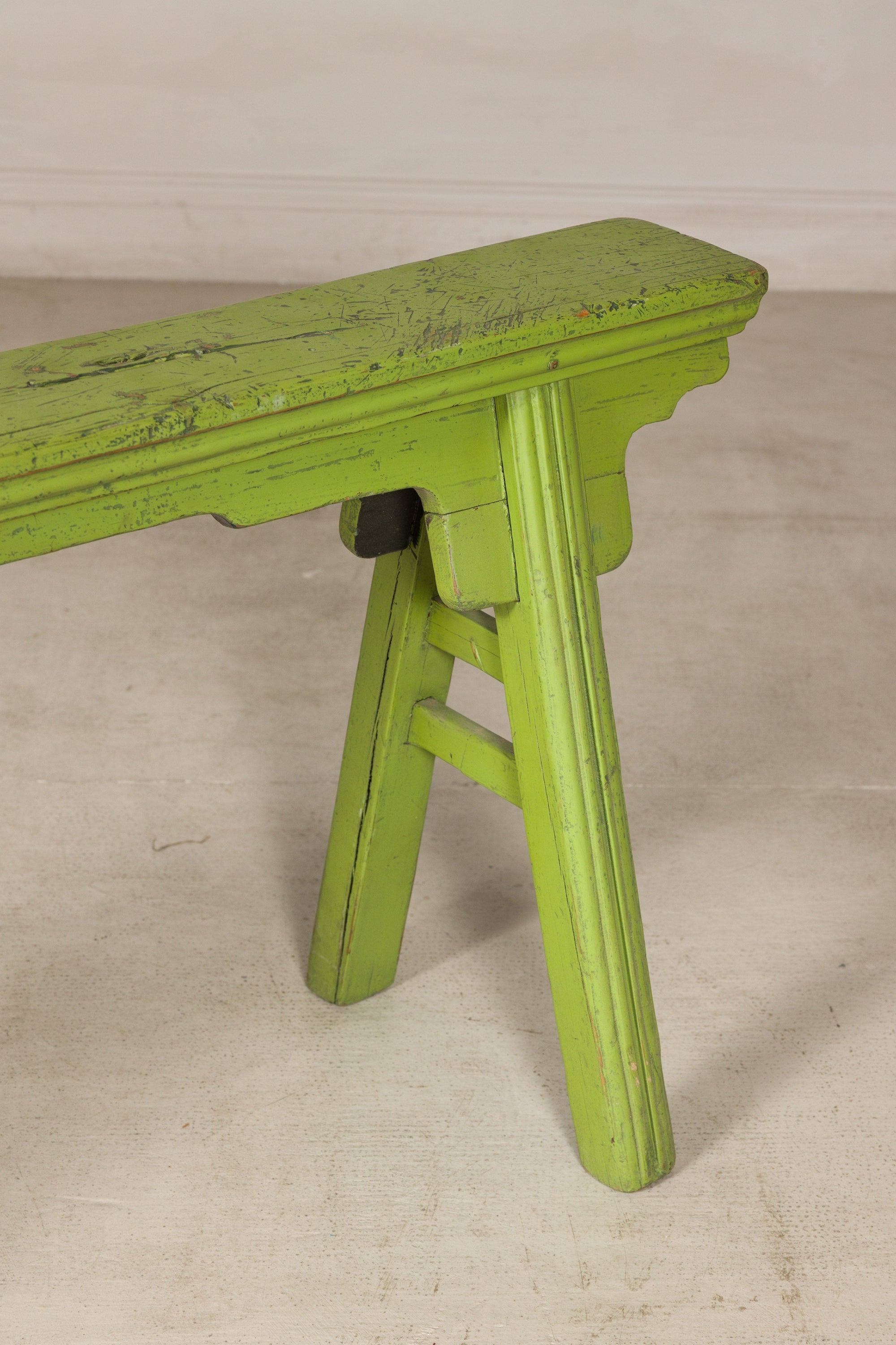 Green painted bench with A-frame supports, three-quarter end view