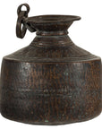Copper hand-hammered vintage metal jug with round body and ring handle, close-up on plain background.