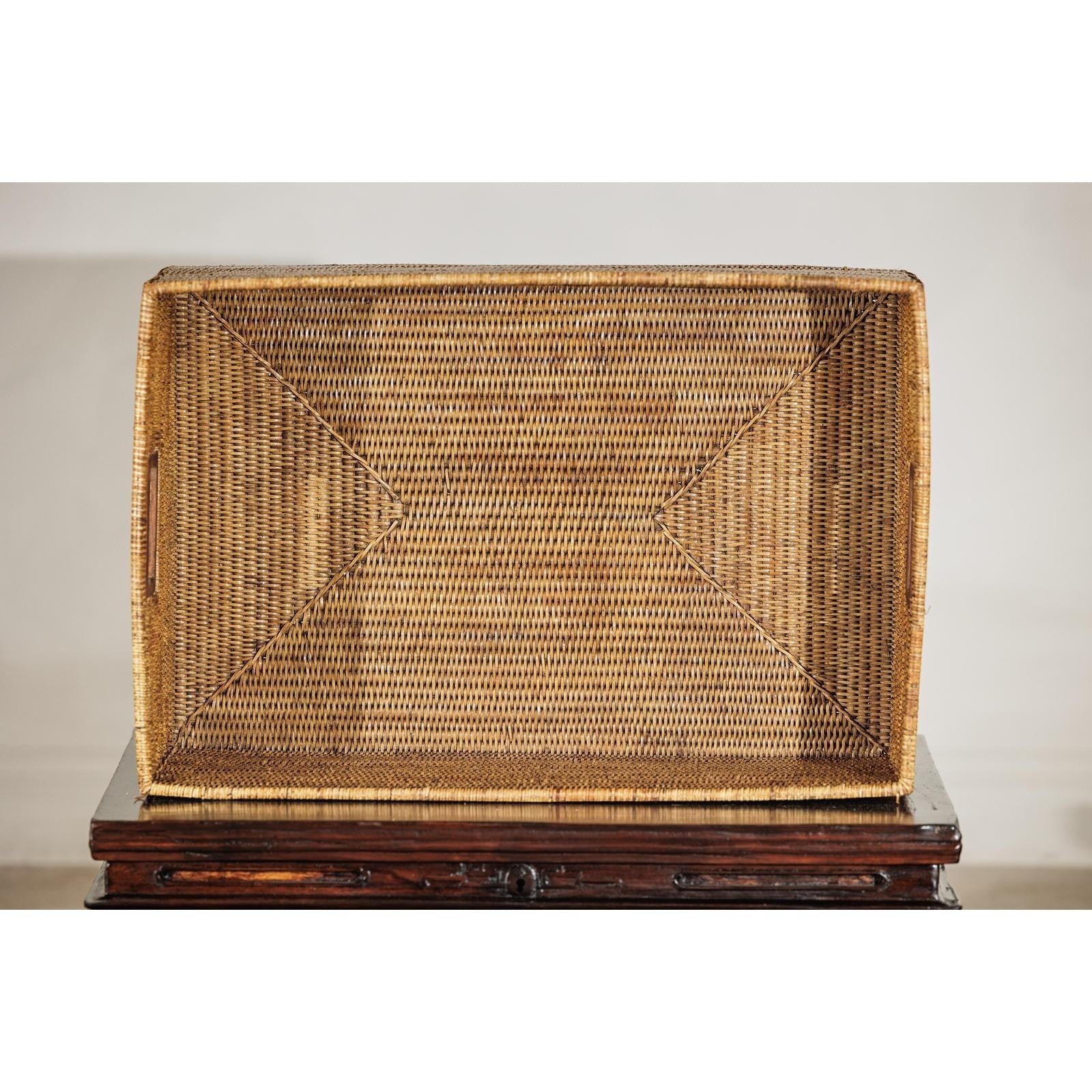 Woven rattan box on a wooden stand against a plain background