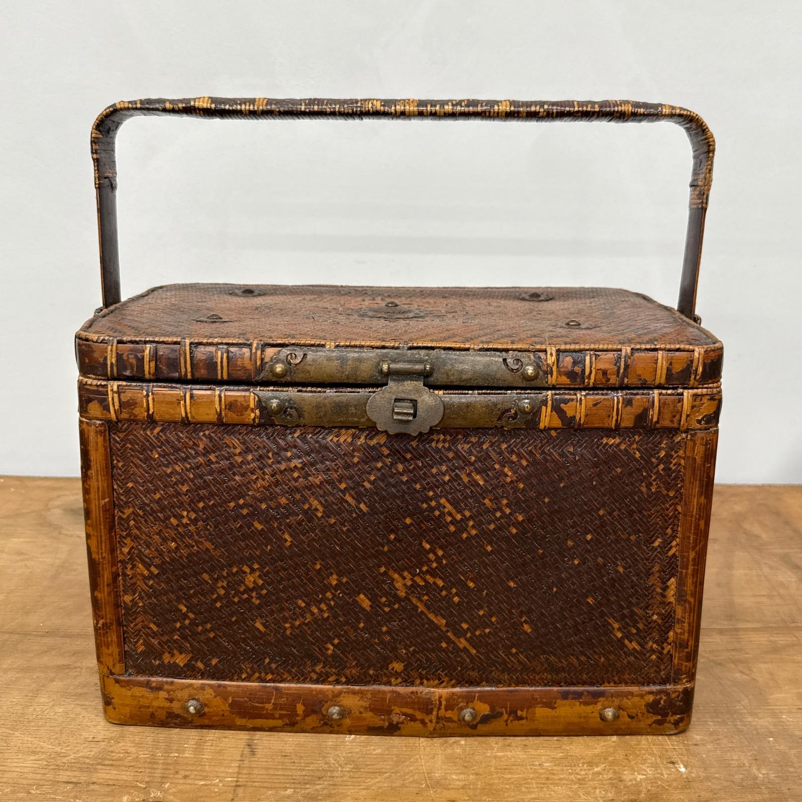 The Woven Rectangular Picnic Basket with Handle &amp; Hinged Lid sits on a wooden surface, its textured brown finish and metal latch showcasing vintage Southeast Asian craftsmanship and rustic charm.