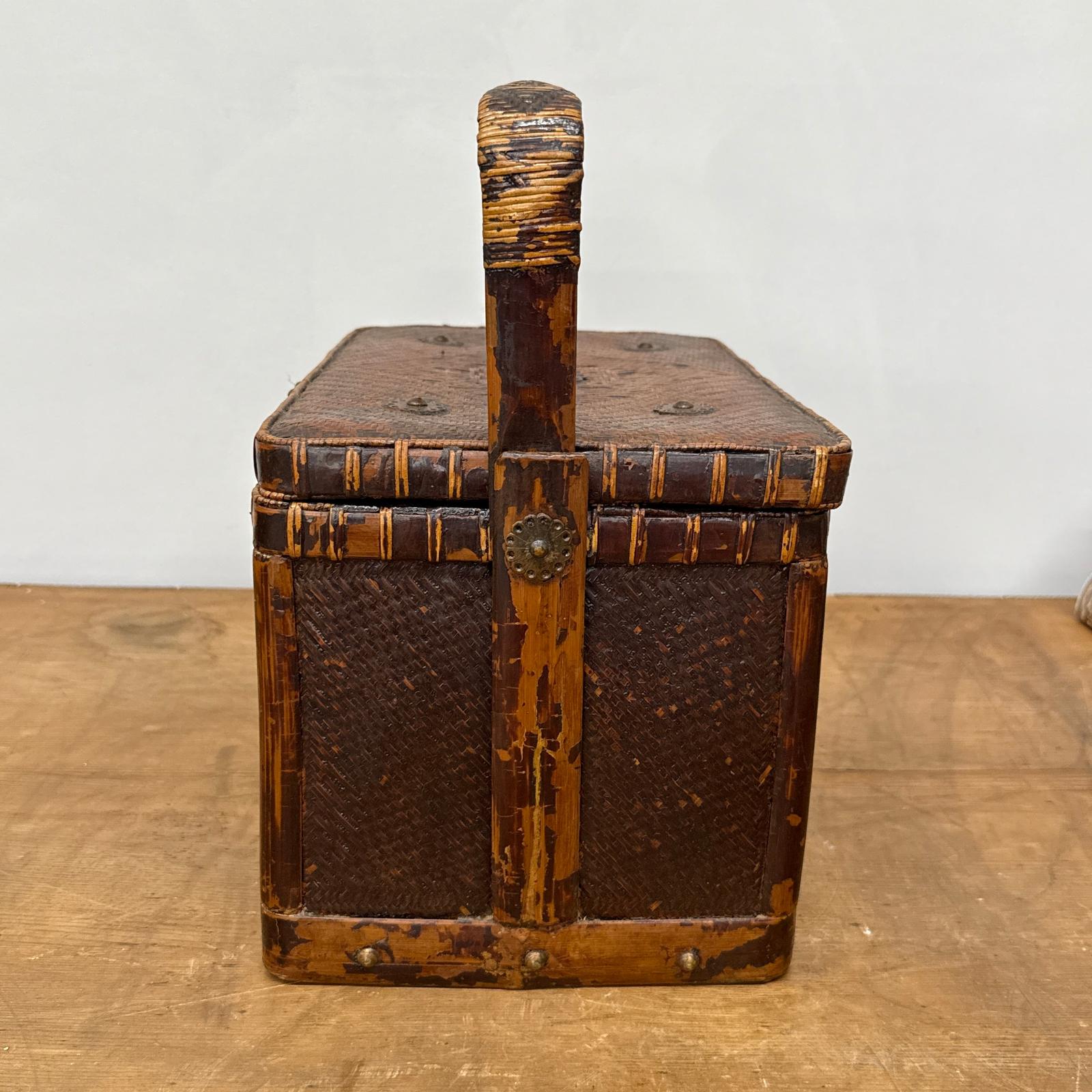 The Woven Rectangular Picnic Basket with Handle &amp; Hinged Lid features a vintage rattan design, wooden frame, and metal accents. Signs of wear highlight its classic Southeast Asian craftsmanship and timeless appeal.