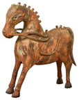 Rust-colored carved wooden horse with decorative saddle, vintage Indian style, close-up on plain background.