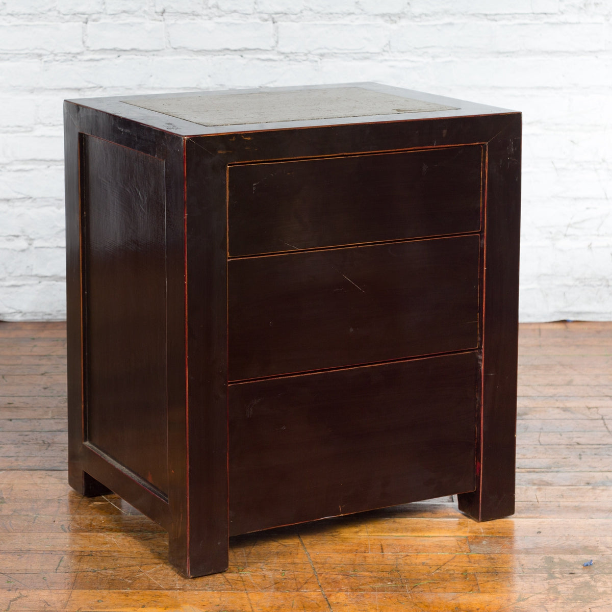 Black lacquer antique Chinese bedside cabinets with Ming Dynasty tops against a white brick wall.
