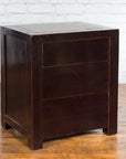 Black lacquer antique Chinese bedside cabinets with Ming Dynasty tops against a white brick wall.