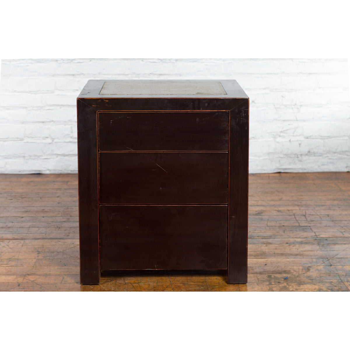 Black lacquer wood bedside cabinets with Ming Dynasty tops on wood floor against white brick wall.