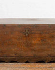 Brown wooden Indian vintage wedding chest with brass foliage décor and multiple compartments on wooden floor by white wall.