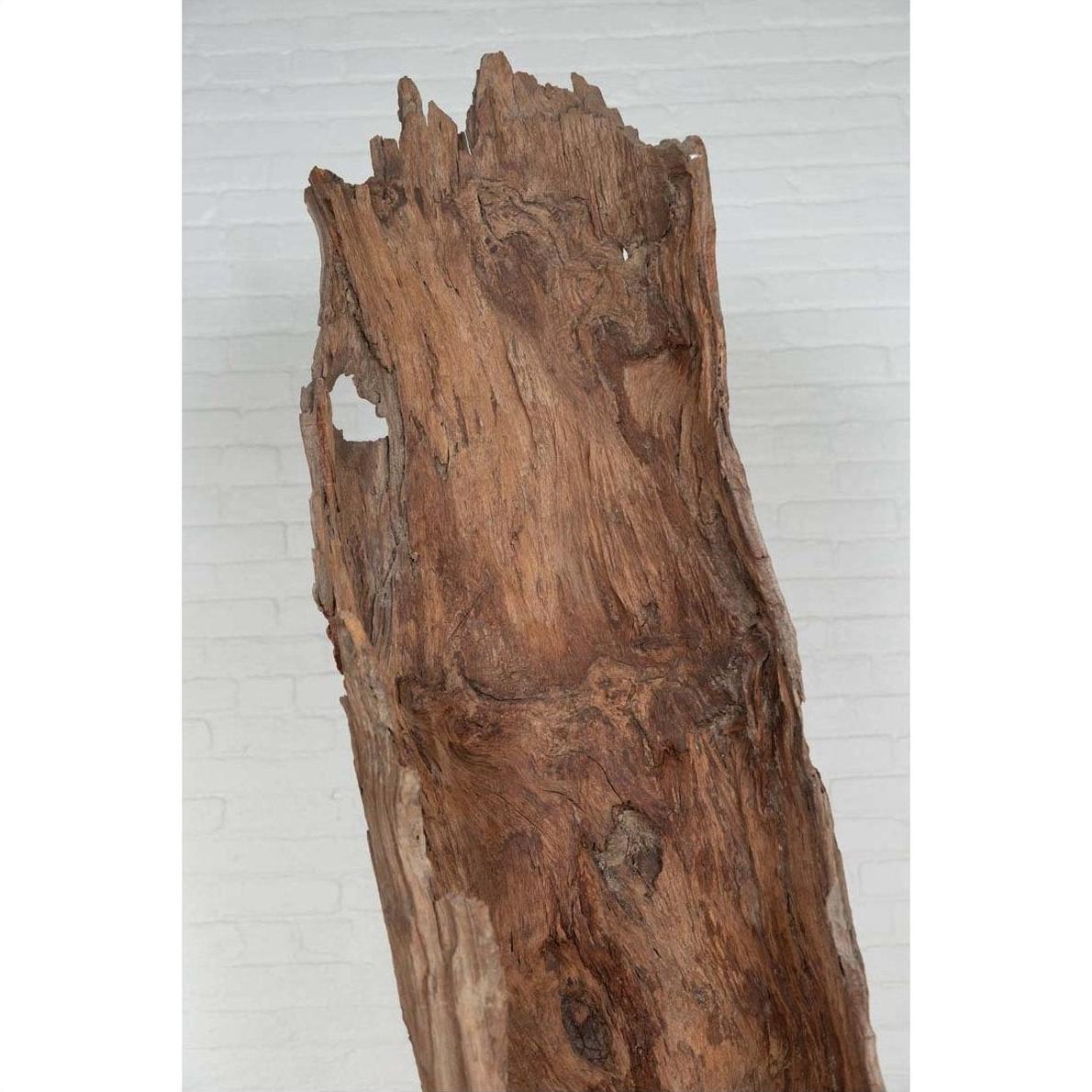 Brown driftwood carving, wood sculpture displayed indoors against a white brick wall background.