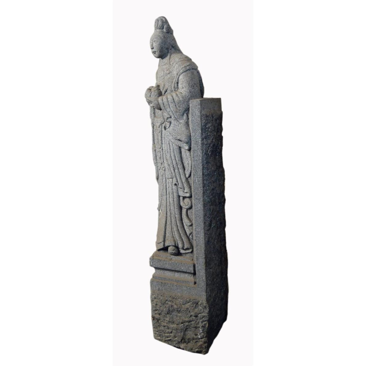 Grey stone hand-carved guardian sculpture of a woman in traditional dress, antique 19th century, indoors.