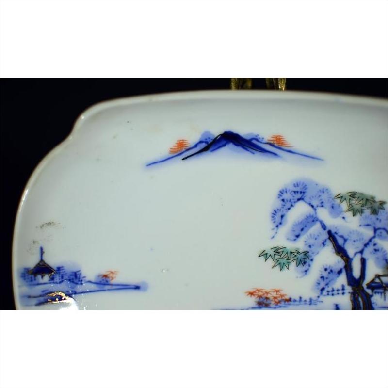 Close-up of blue and white porcelain bowl with hand-painted mountain landscape, trees, and house.
