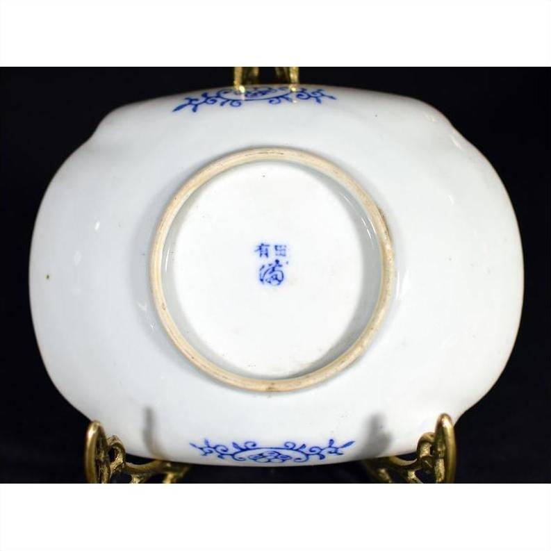 Close-up of the white porcelain underside of an antique Asian hand-painted bowl on a brass stand.