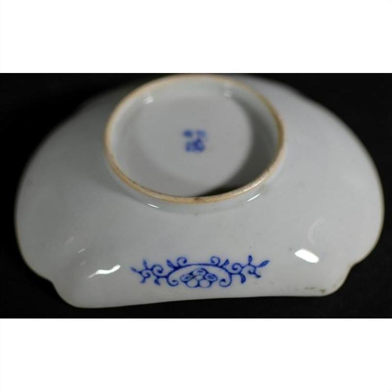Blue and white porcelain bowl upside down, hand painted with floral design and maker’s mark on black background.