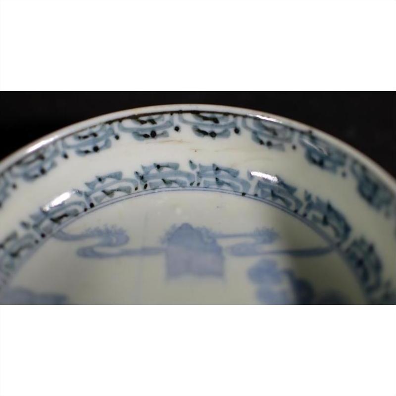 Close-up of blue and white porcelain bowl rim with intricate hand painted Asian patterns.