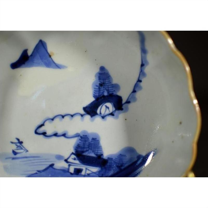 Close-up of blue and white hand painted porcelain bowl with gold scalloped edge, antique Asian design.