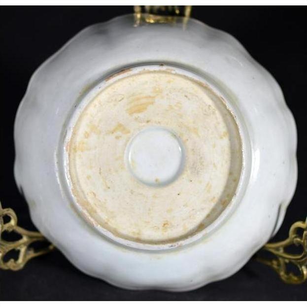 Close-up of underside of antique Asian hand painted porcelain bowl with circular foot ring on gold stand.