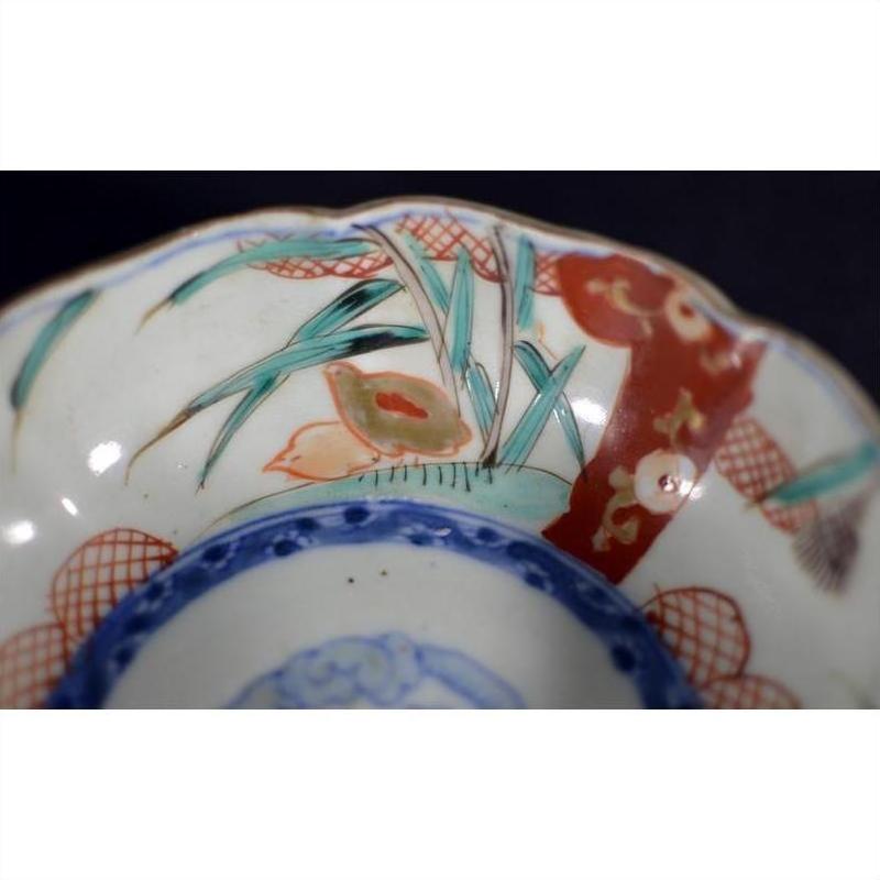 Close-up of antique Asian porcelain bowl with vibrant red, blue, and green hand-painted floral patterns.