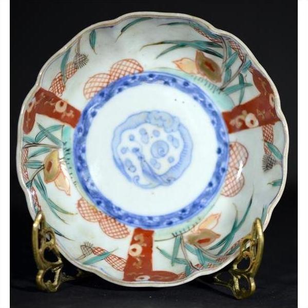 Close-up of an antique porcelain bowl with floral and geometric motifs on an ornate brass stand.