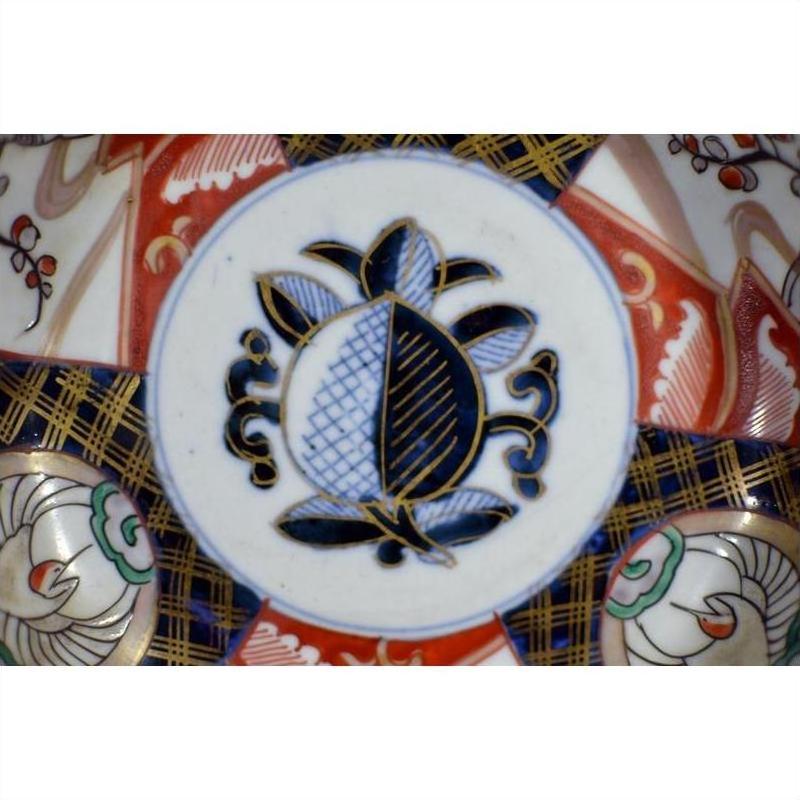 Close-up of antique Asian porcelain bowl with blue and black pomegranate and vibrant floral patterns.