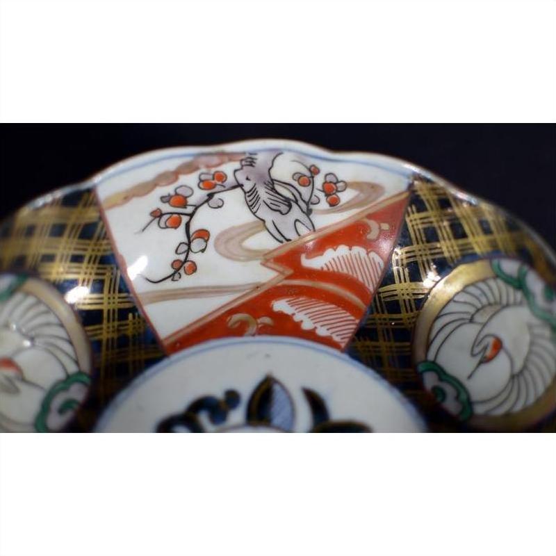 Close-up of red, gold, green, and white porcelain bowl with hand-painted floral and geometric designs.