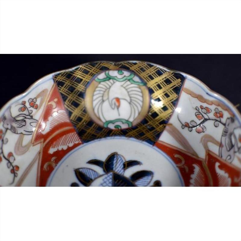 Close-up of antique Asian porcelain bowl with red, gold, green, and blue hand-painted floral patterns.