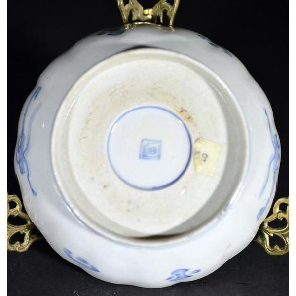 Close-up of the bottom of an antique blue and white porcelain bowl with hand-painted designs and a square maker's mark.