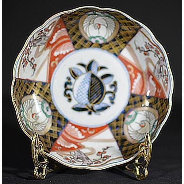 Close-up of red, blue, gold, and black hand-painted porcelain bowl on a gold stand.