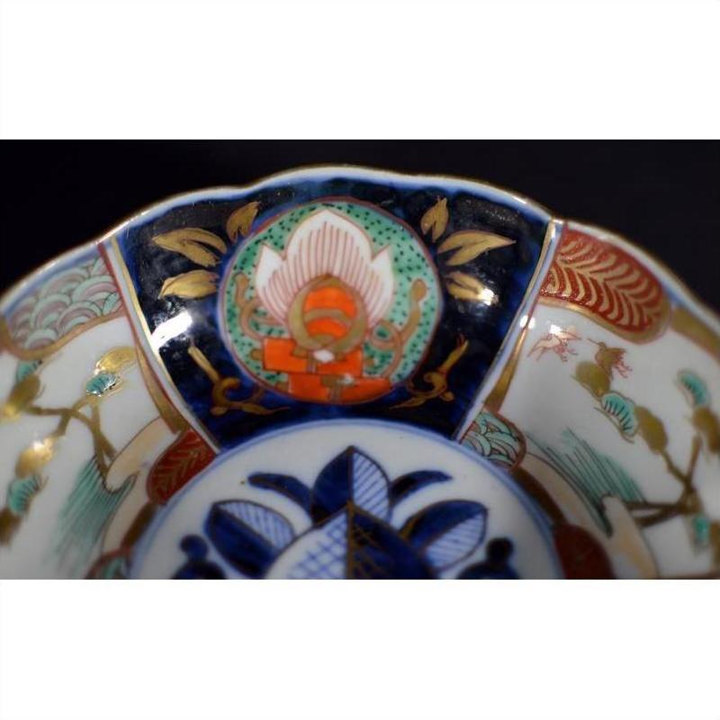 Close-up of antique Asian porcelain bowl with intricate blue, gold, red, and green patterns on the rim.