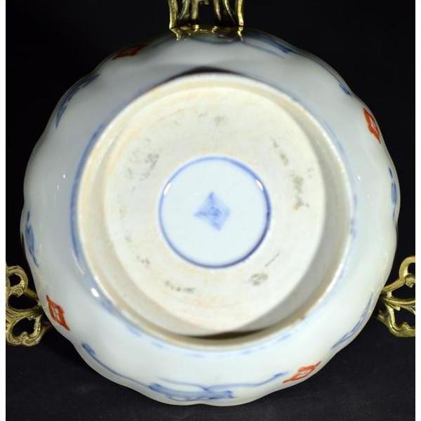 Close-up of the underside of a blue and gold antique Asian hand painted porcelain bowl with maker's mark and metal handles.