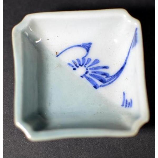 Close-up of blue and white hand-painted porcelain dish with abstract design, displayed on a dark modern surface.