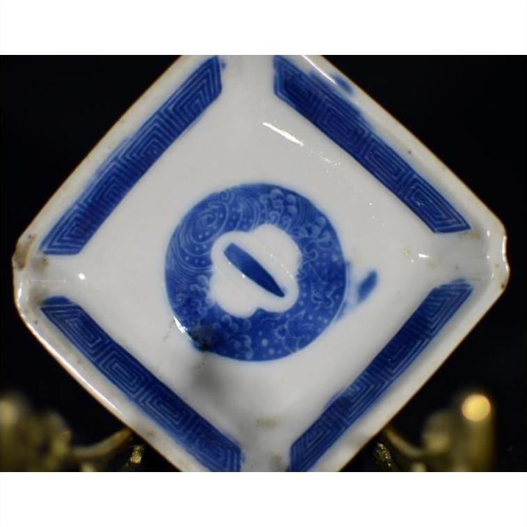 White porcelain dish with hand painted circular symbol and geometric border, antique Asian style, angled view.