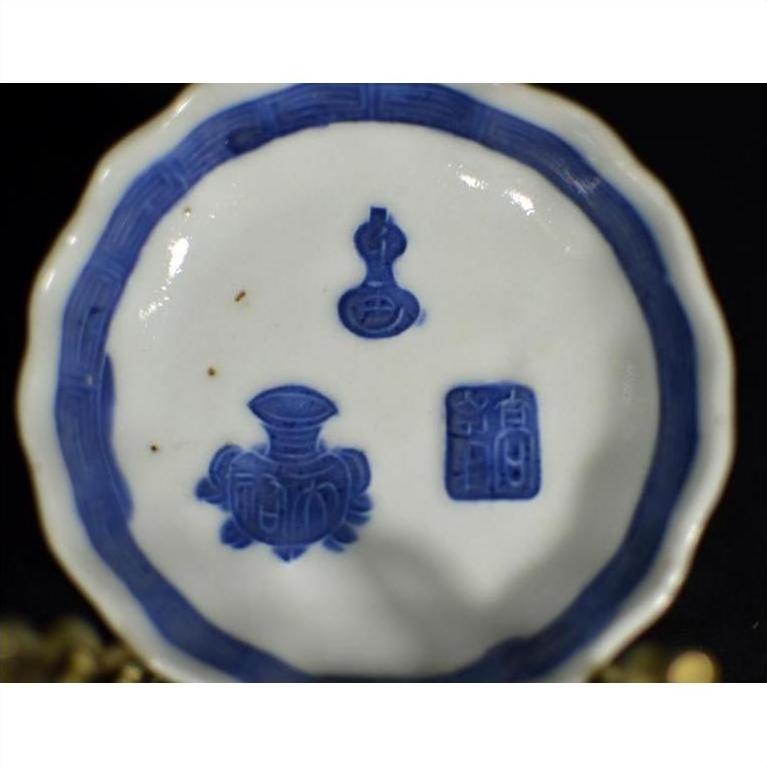 Close-up of blue and white porcelain dish with hand painted Chinese symbols, floral designs, and bold blue rim.