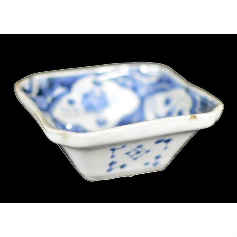 Close-up of antique blue and white hand painted porcelain dish with designs inside and out, on black background.