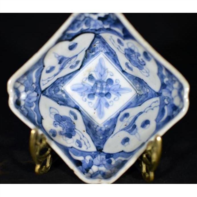 Blue and white hand-painted porcelain dish with floral patterns on a metal display stand.