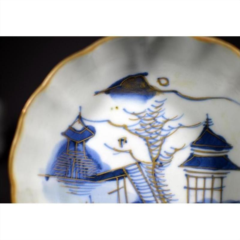 Close-up of blue and gold porcelain plate with hand painted Asian landscape and pagoda island motif.