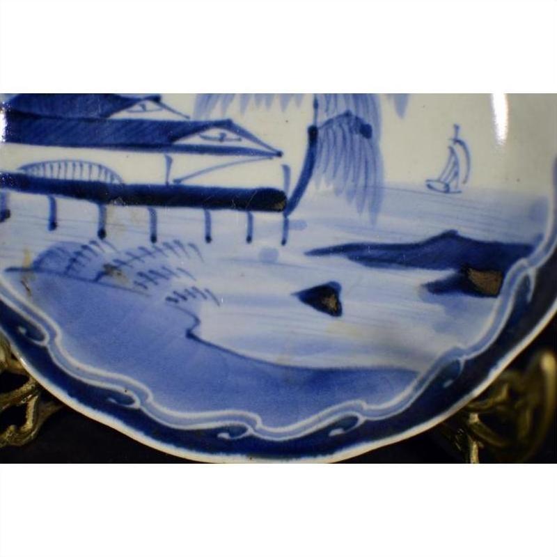 White porcelain plate with hand painted river pavilion and willow grove, close-up of chinoiserie decor pattern.