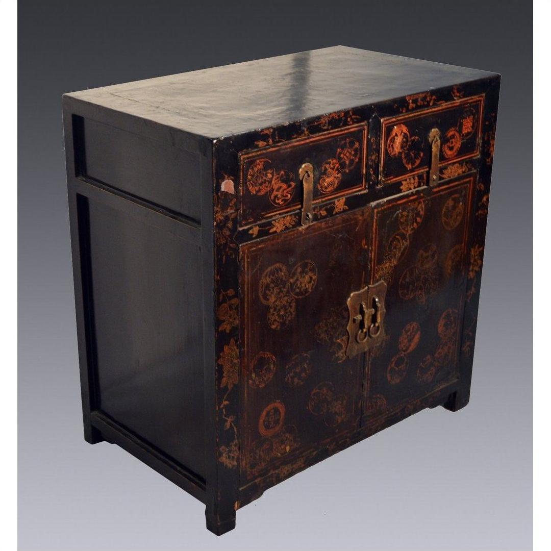 Black wood Chinese Chinoiserie cabinet with two drawers, gold floral accents, and scalloped hardware, front view.