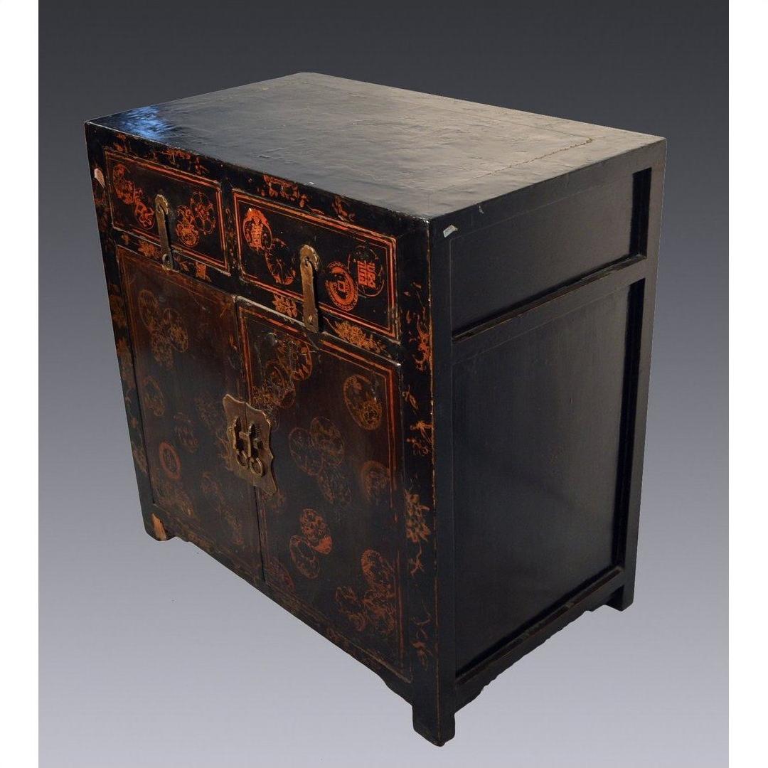 Black lacquered Chinese cabinet with gold detailing, scalloped hardware, and red patterned doors, front view.
