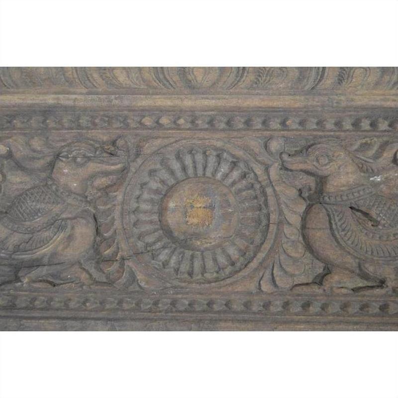 Brown wooden antique Indian carving with two mythical birds and lotus motif, bordered by intricate patterns, close-up.
