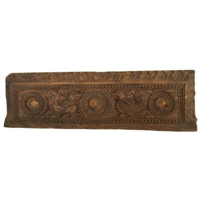 Close-up of brown wooden panel with ornate Indian carving, showing two birds and circular floral motifs.