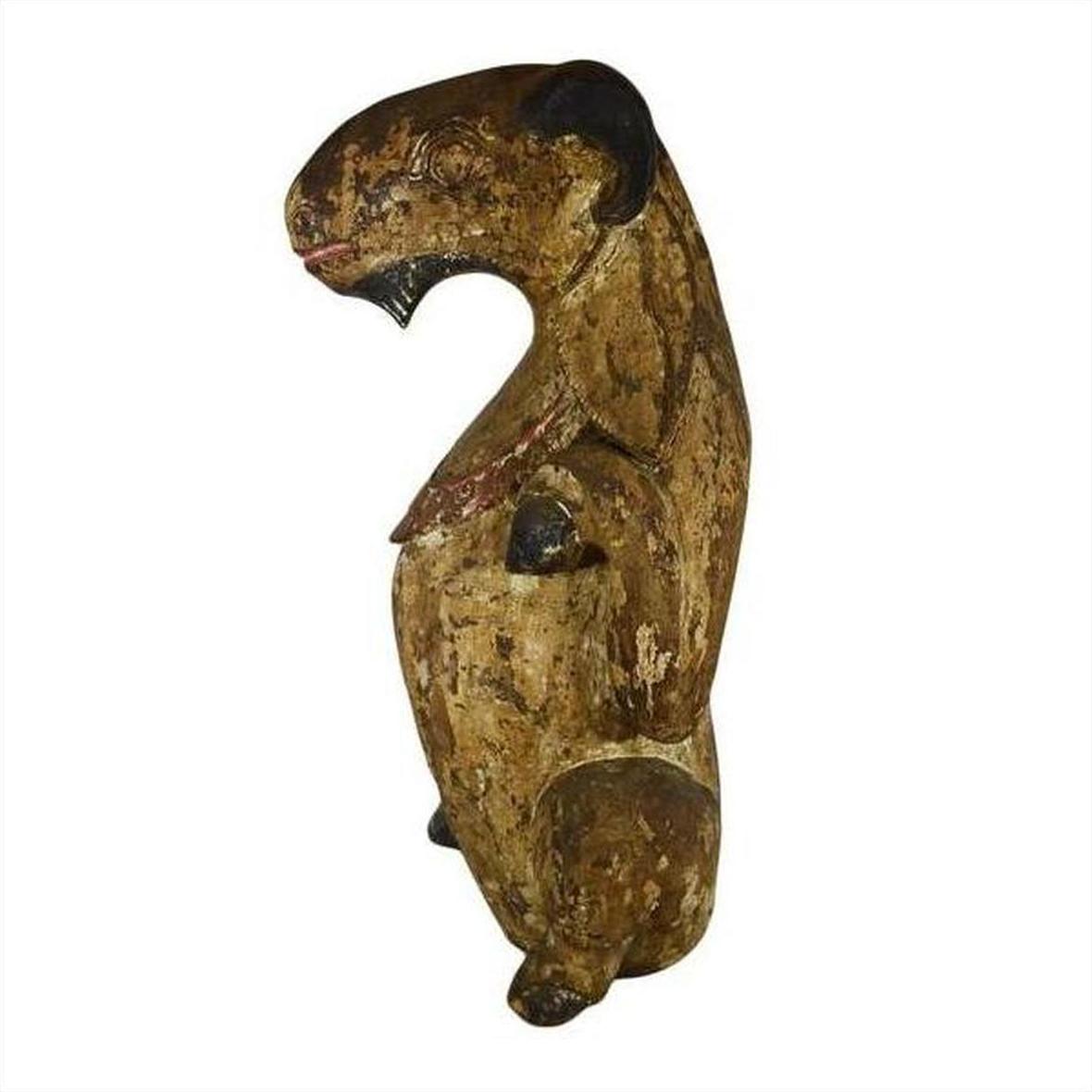 Brown hand-carved wood seated goat sculpture with rounded features and worn paint, antique Burmese, side view.