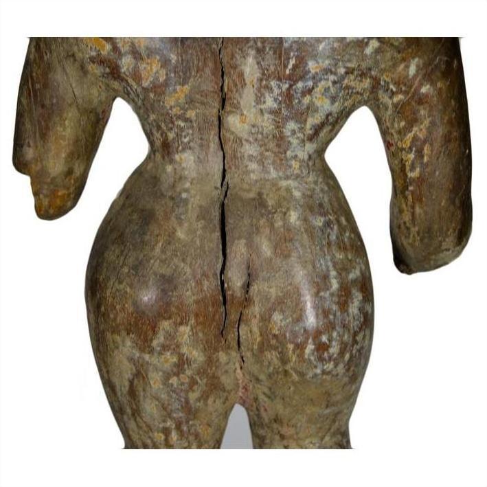Brown weathered and cracked wooden sculpture of a human back and hips on a plain white background.