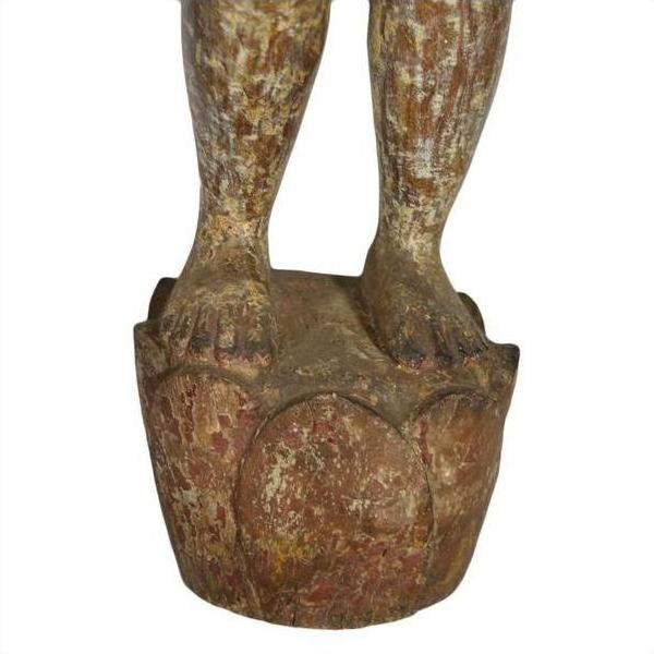Close-up of weathered red-brown wood Burmese temple carving feet on detailed lotus base with aged patina.