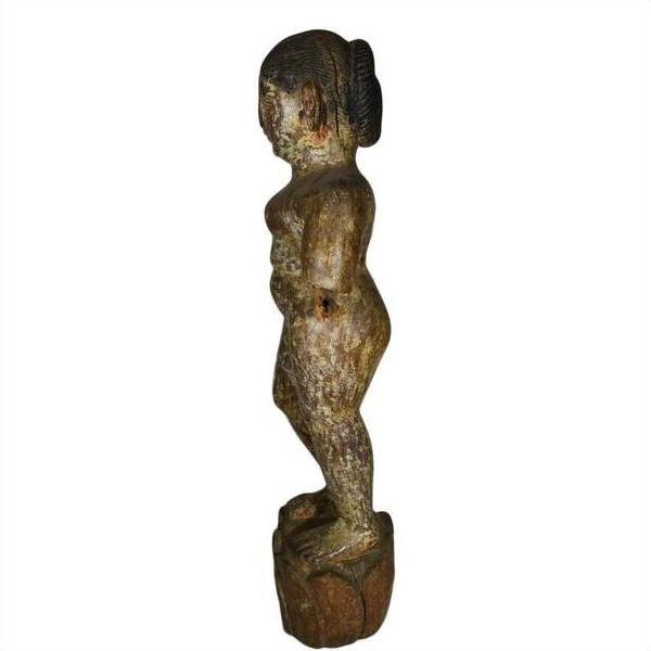Weathered wood statue of nude child, side view, antique Burmese temple carving, arms at sides.