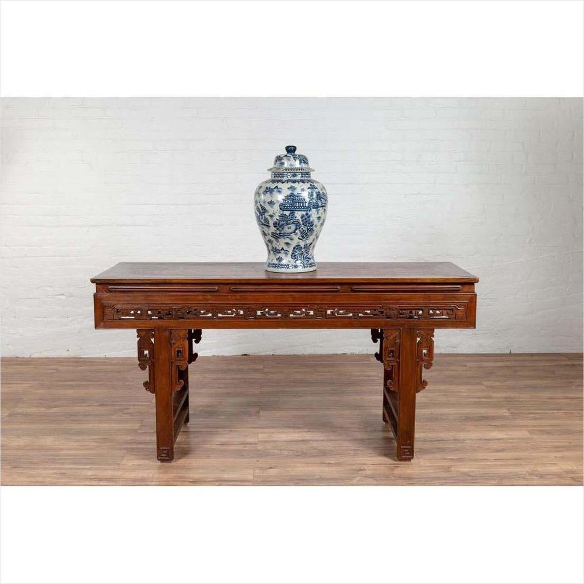 Antique dark wood Chinese altar console table with overhang top, set against a white brick wall and wooden floor.
