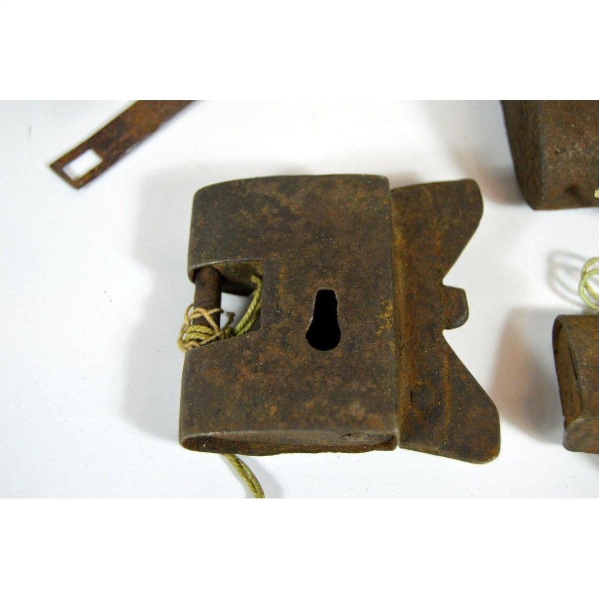 Close-up of antique Chinese and Indian metal locks with keyholes and string on a white surface.