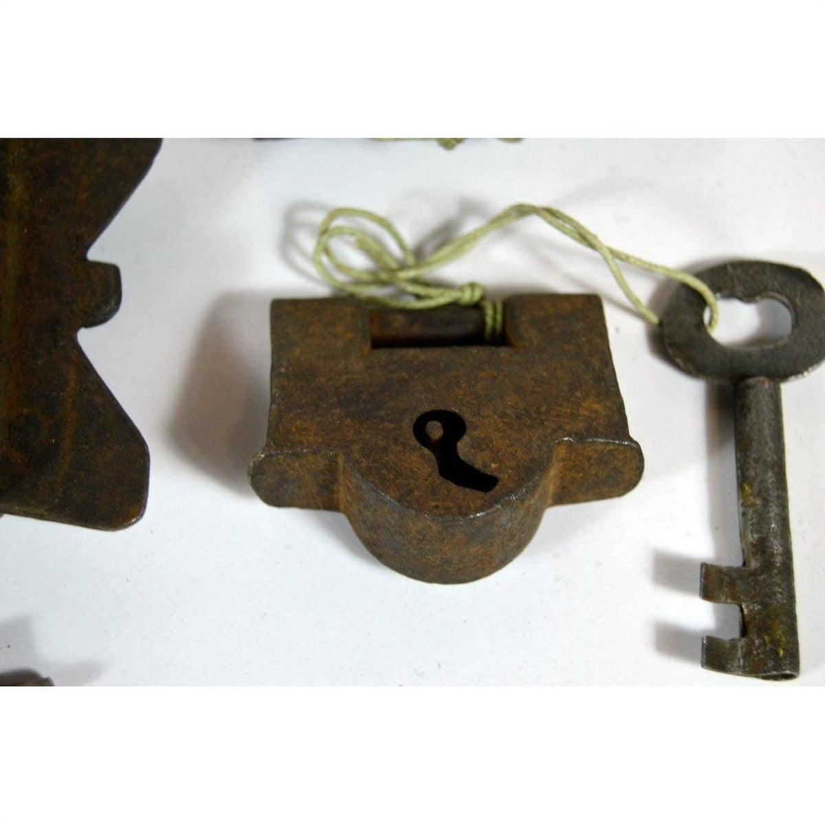 Close-up of antique metal Chinese and Indian locks with original keys displayed on a white surface.