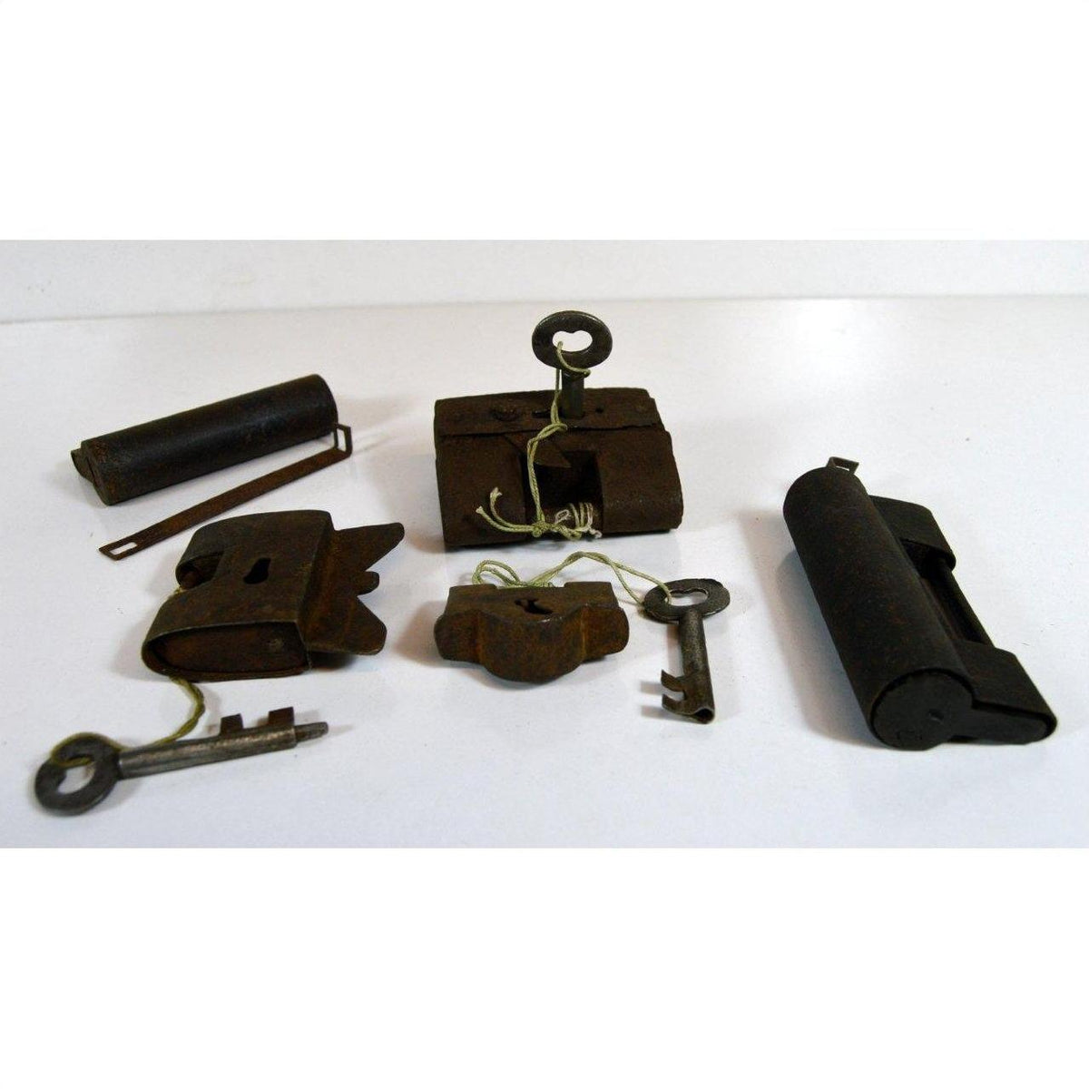 Brass and iron antique Chinese and Indian locks with original keys, some tied, displayed on a white surface.