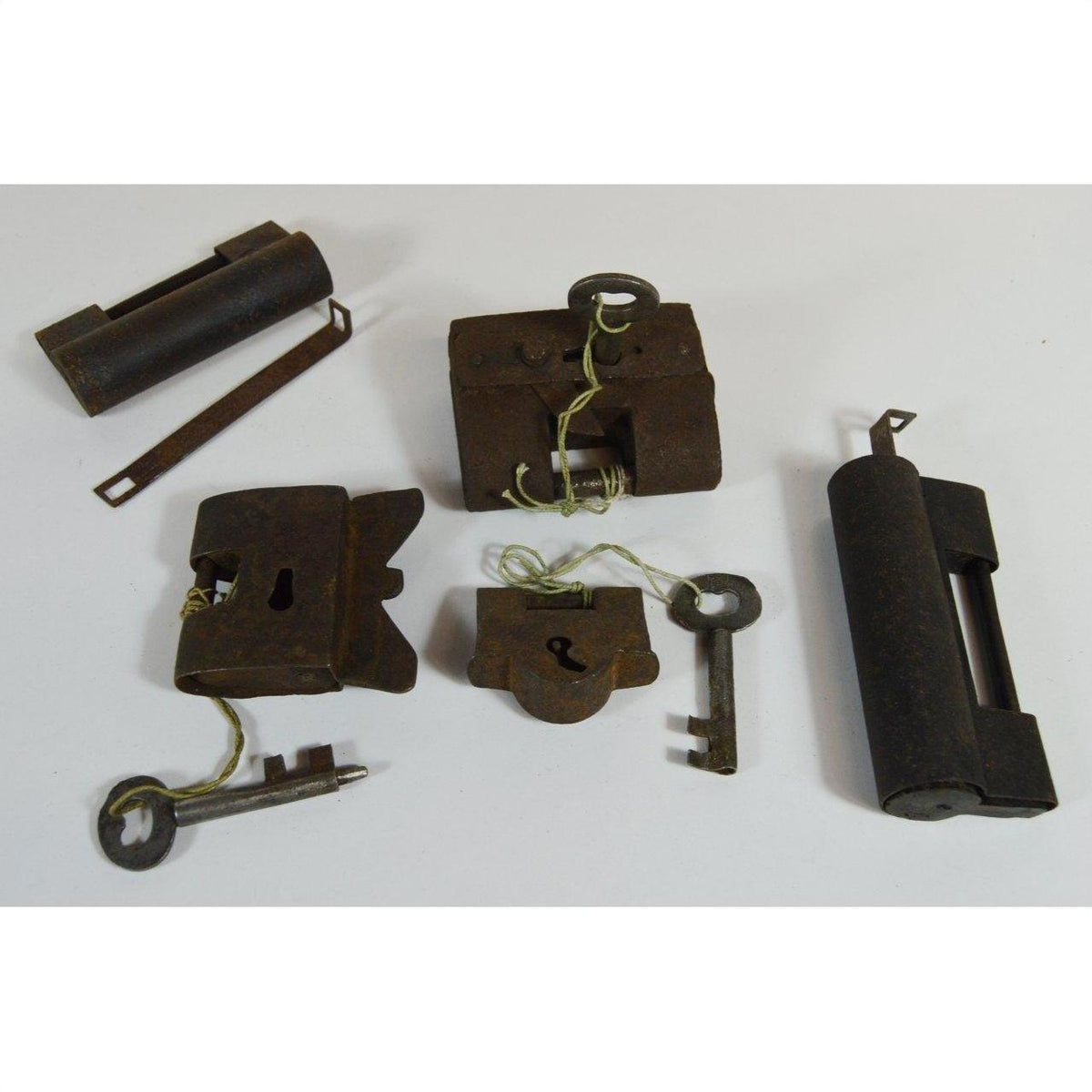Close-up of five antique metal Chinese and Indian locks with original keys on a white surface.